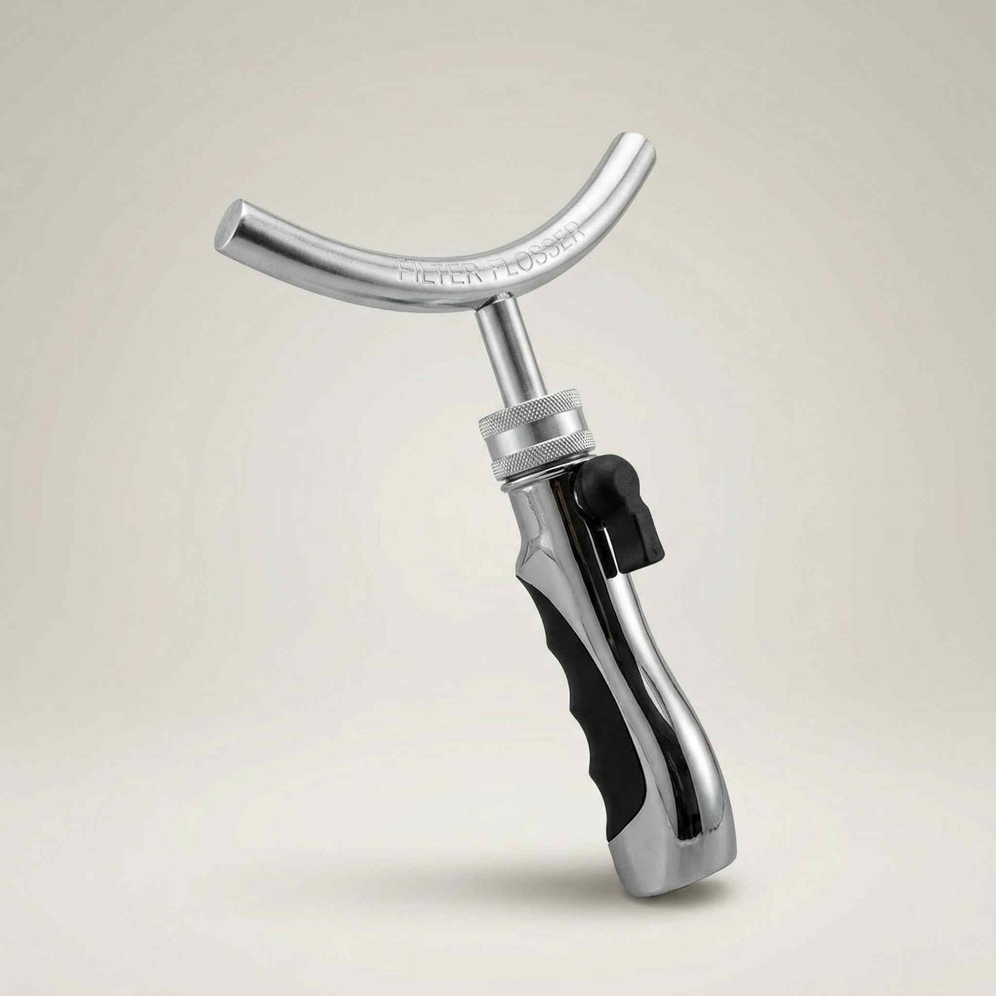 Metal tool with a black handle on a beige background